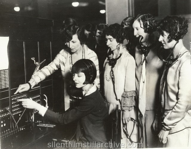 SF TO CLEVELAND: NY ACME: TWO PRINTS CHI ACME         NOV 17
Oh see the pretty telephone operator! Who is she? None other than Colleen Moore, versatile screen star. Her newest picture shows her as a phone girl, so here she is, learning from Los Angeles exchange girls just what happens when you juggle the hook. -- L A Bureau
