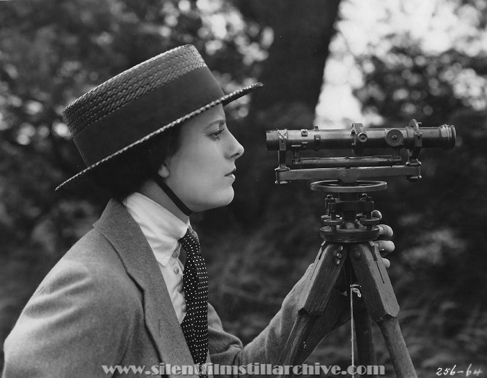Alice Calhoun looks through a theodolite in PEGGY PUTS IT OVER (1921)